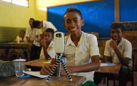 A school boy from Timor Leste has his camera on a tripod sitting on his desk.