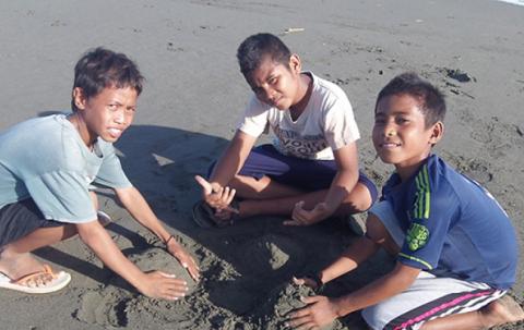 Three boys play in the sand. 