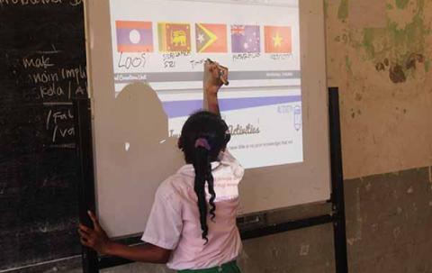 A girl chooses flags from a projection on a whiteboard. 