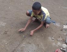 A boy plays marbles. 